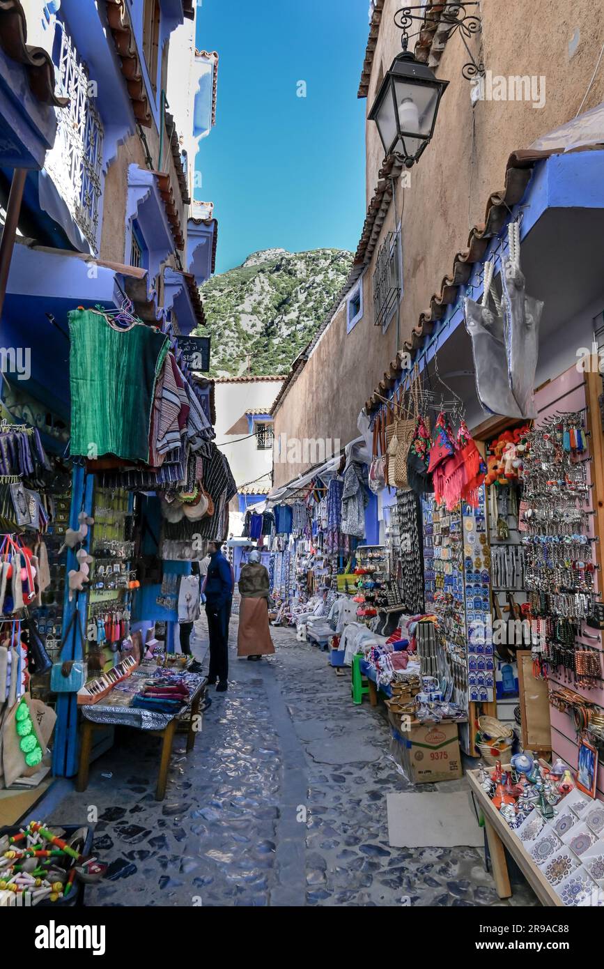 The Riff mountains peak through a small street bazar, in the blue city of Chefchaouen, Morocco Stock Photo