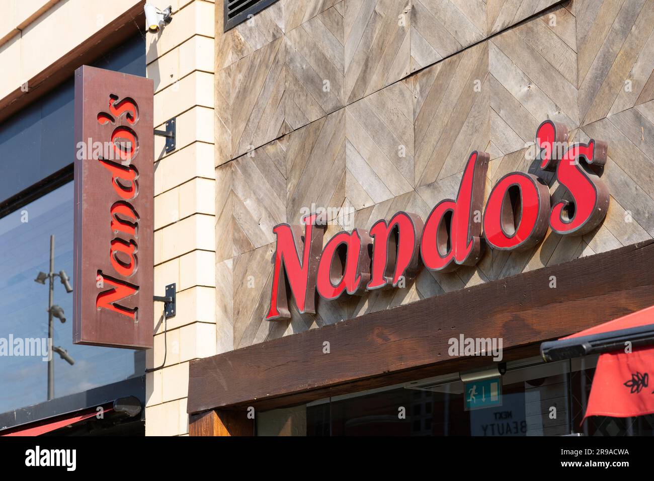 Sign and lettering logo for Nandos restaurant, an afro-portugese chain serving flame grilled chicken on the Oracle Centre Riverside in Reading, UK Stock Photo