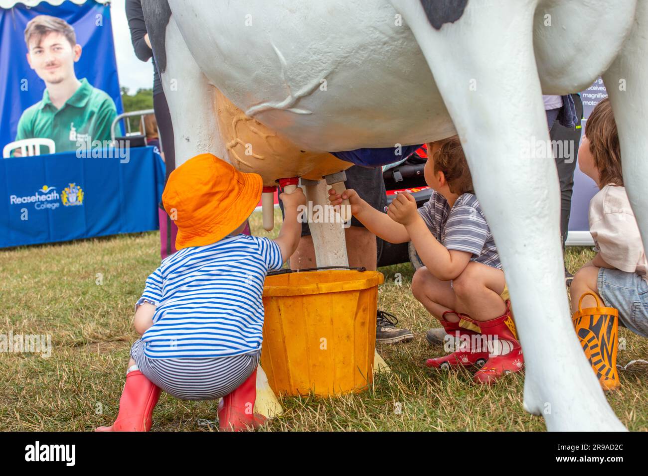 Young children milking a model cow on the Rease heath Reaseheath agricultural collage stand at the 2023 Royal Cheshire show Stock Photo