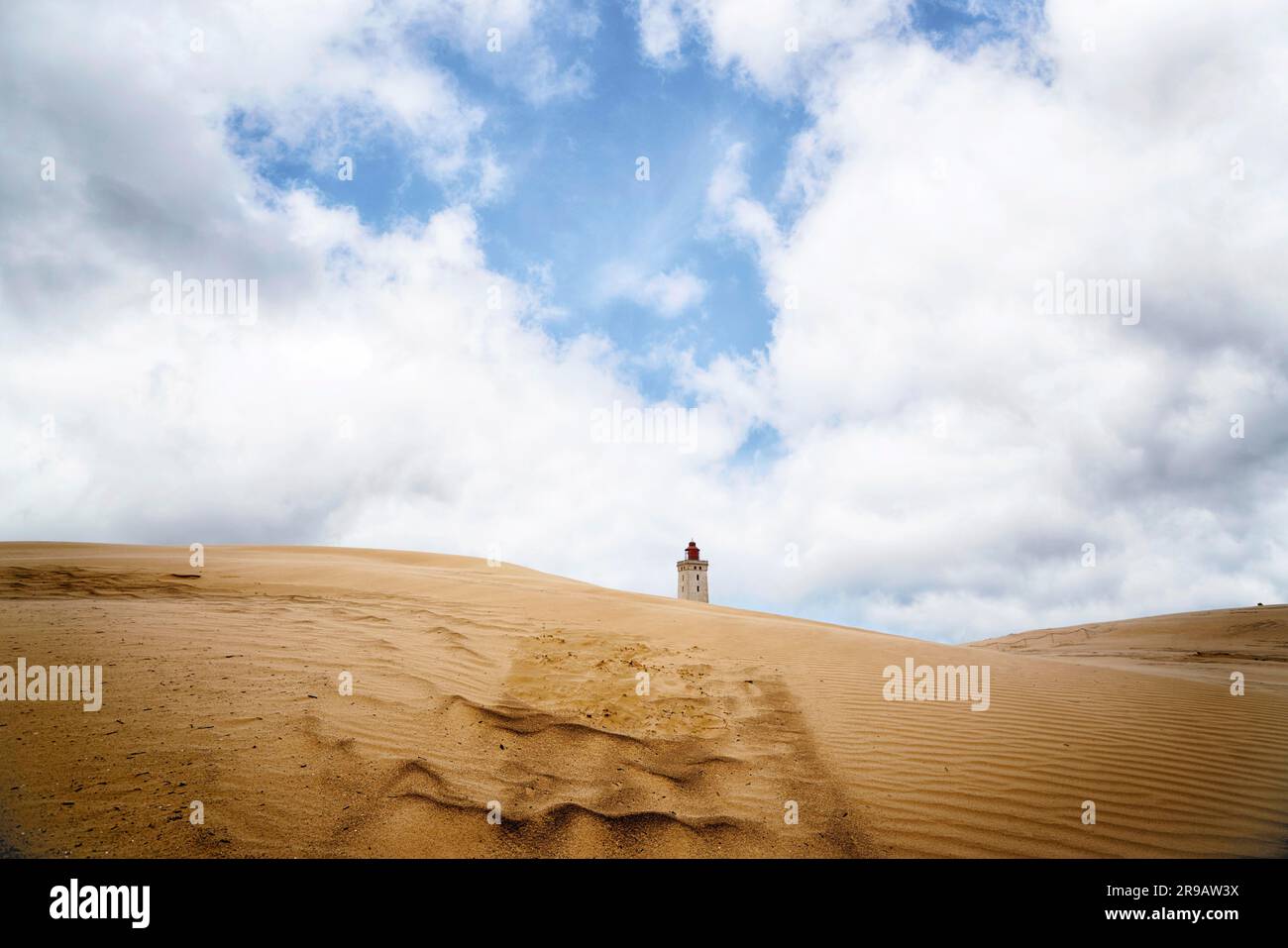 Lighthouse in the middle of a desert under a blue sky on a sandy dune Stock Photo