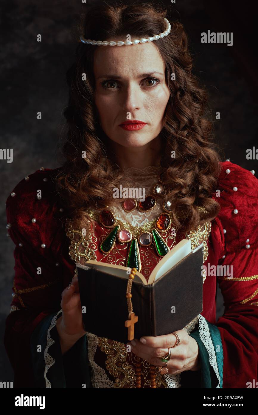 medieval queen in red dress with rosary on dark gray background Stock ...