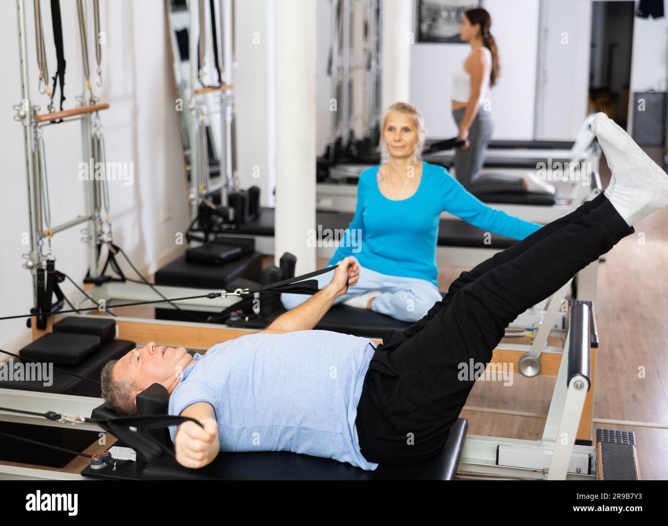 Concentrated old man doing Pilates exercises for lower back while lying