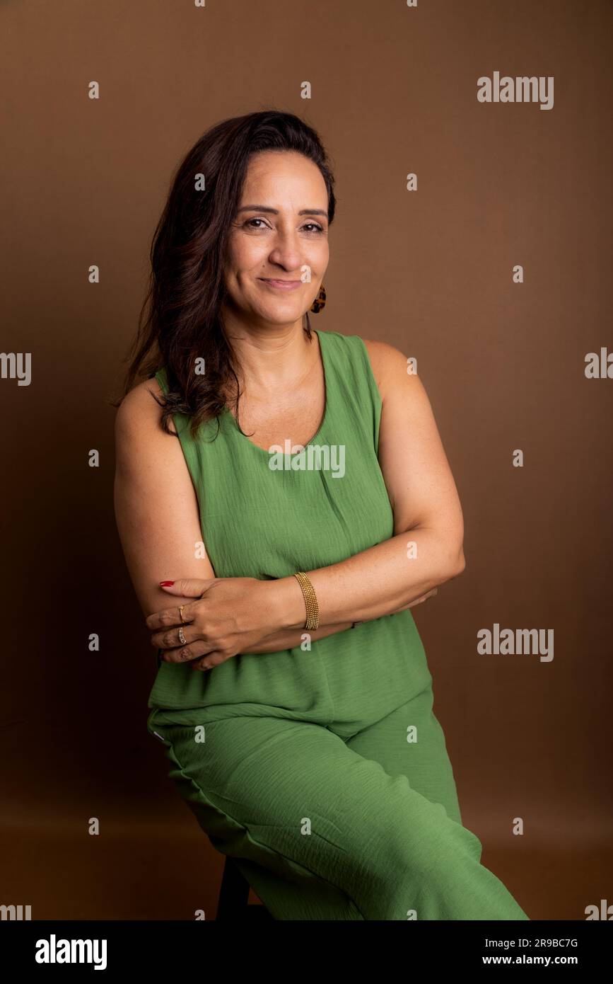 Portrait of beautiful woman, wearing green outfit. Confidence, motivation and maturity concept. Isolated on brown background. Stock Photo