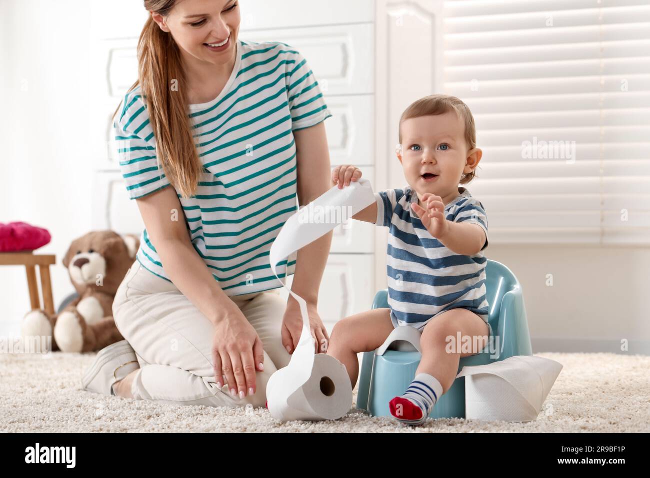 Mother training her child to sit on baby potty indoors Stock Photo Alamy