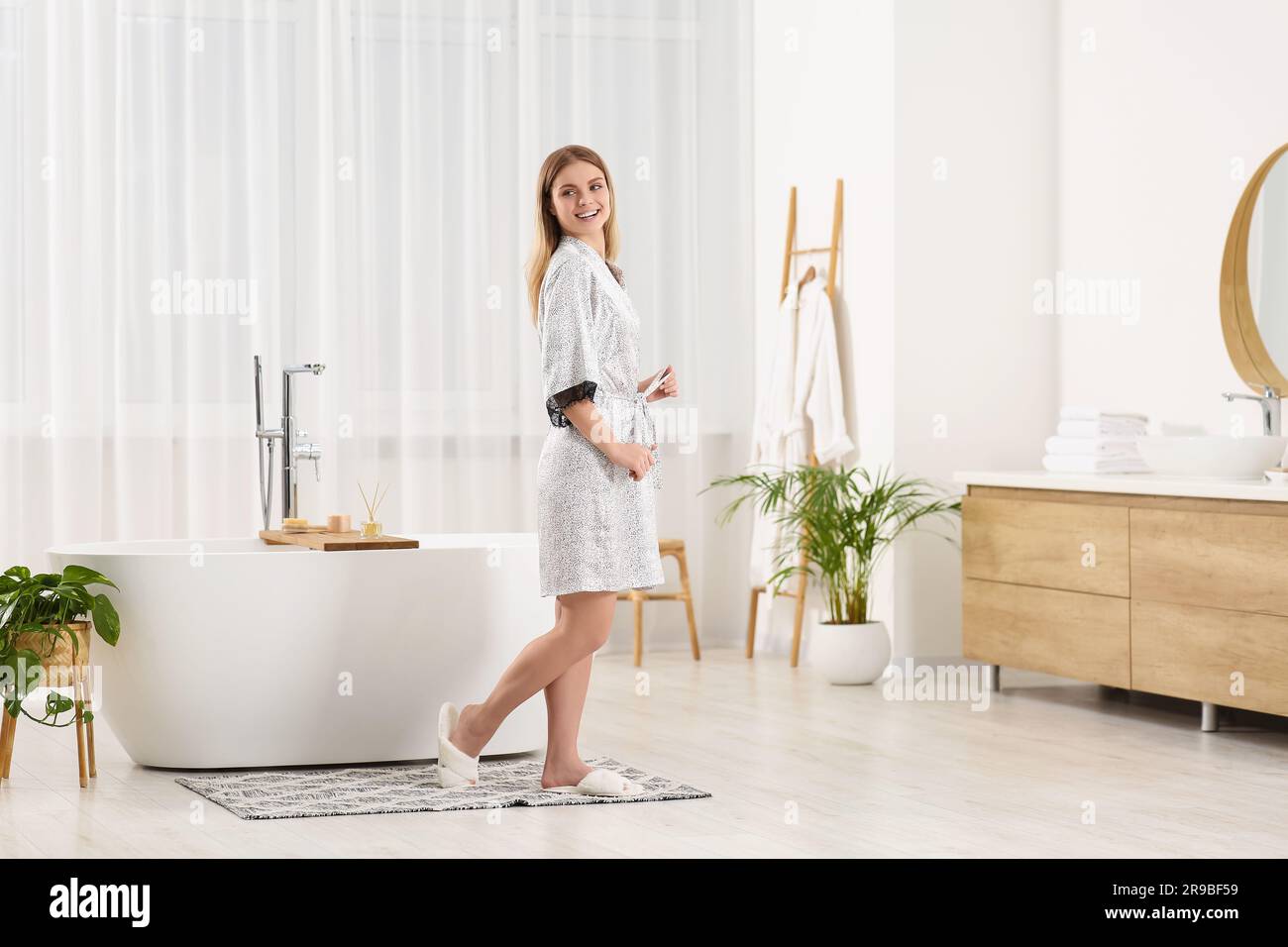Beautiful woman wearing stylish robe near tub in bathroom Stock Photo ...