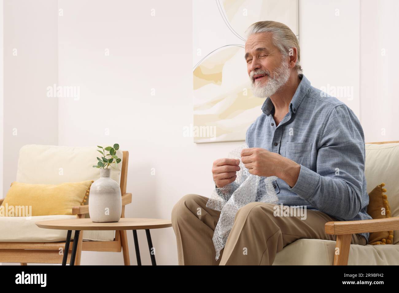 Senior man popping bubble wrap at home. Stress relief Stock Photo - Alamy