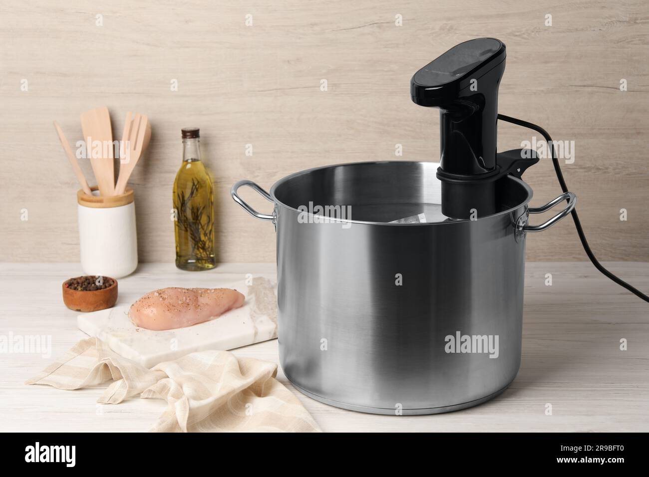 Thermal immersion circulator in pot and meat on white wooden table. Sous vide cooking Stock