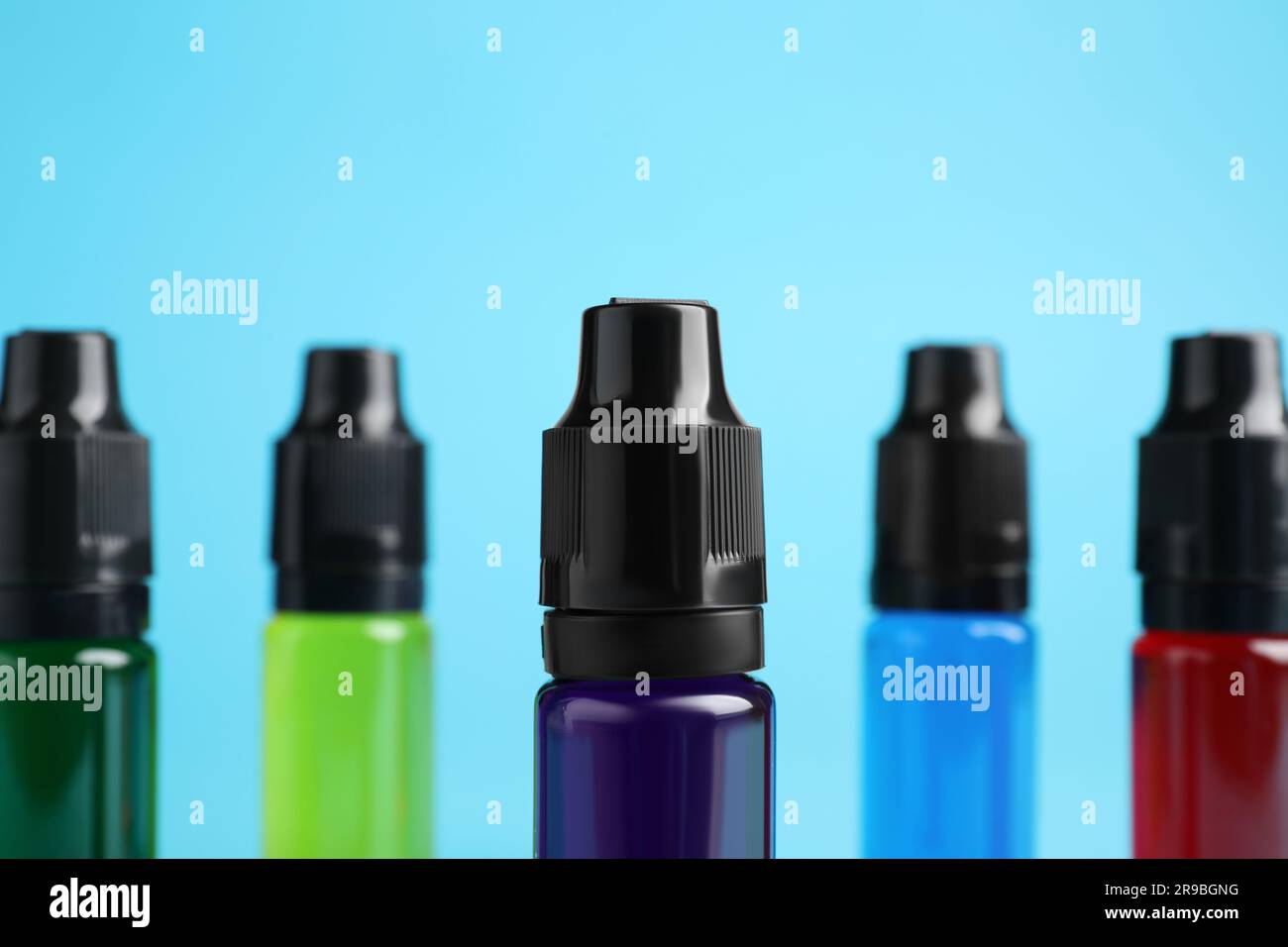 Bottles with different food coloring on light blue background, closeup Stock Photo
