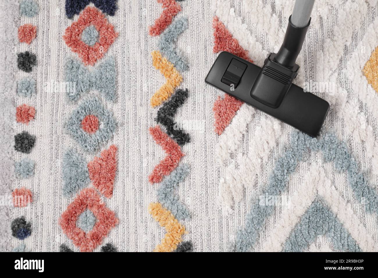 Hoovering carpet with modern vacuum cleaner indoors, top view. Space