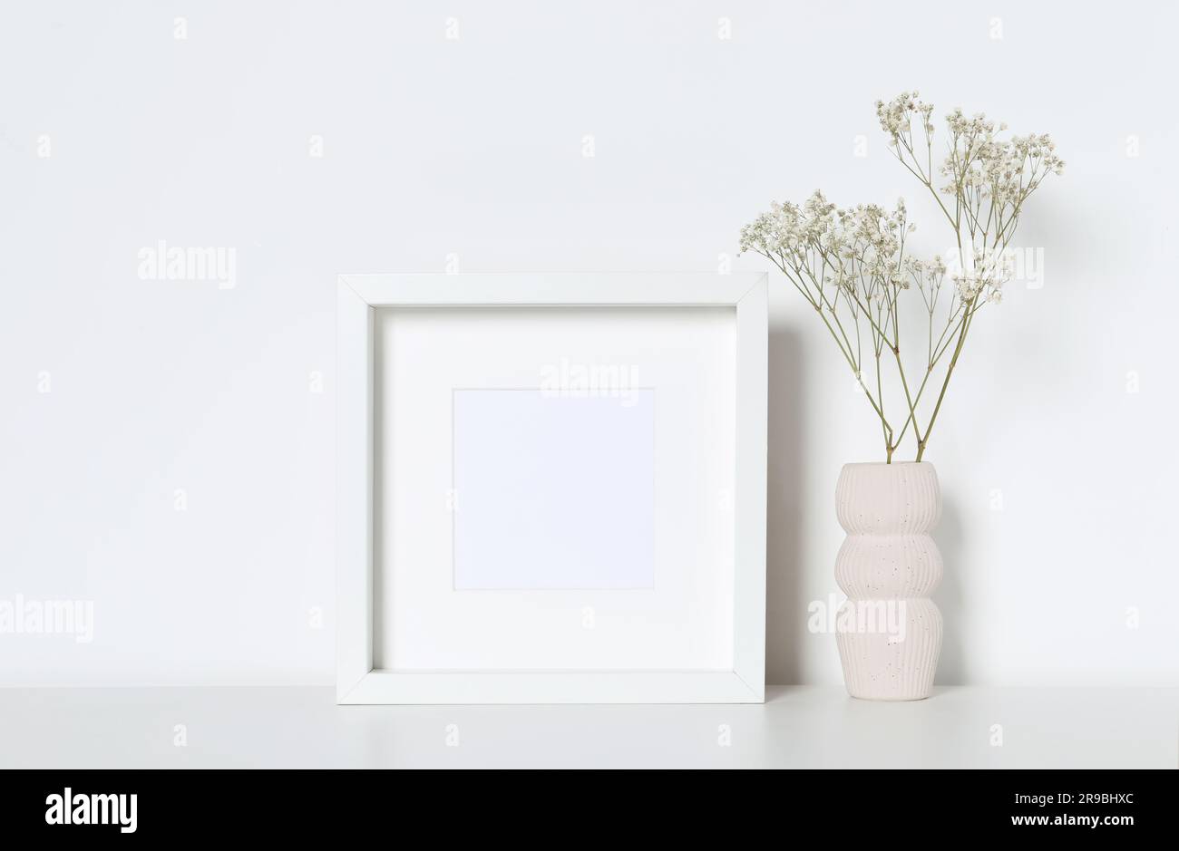 Empty photo frame and vase with dry decorative gypsophila flowers on ...