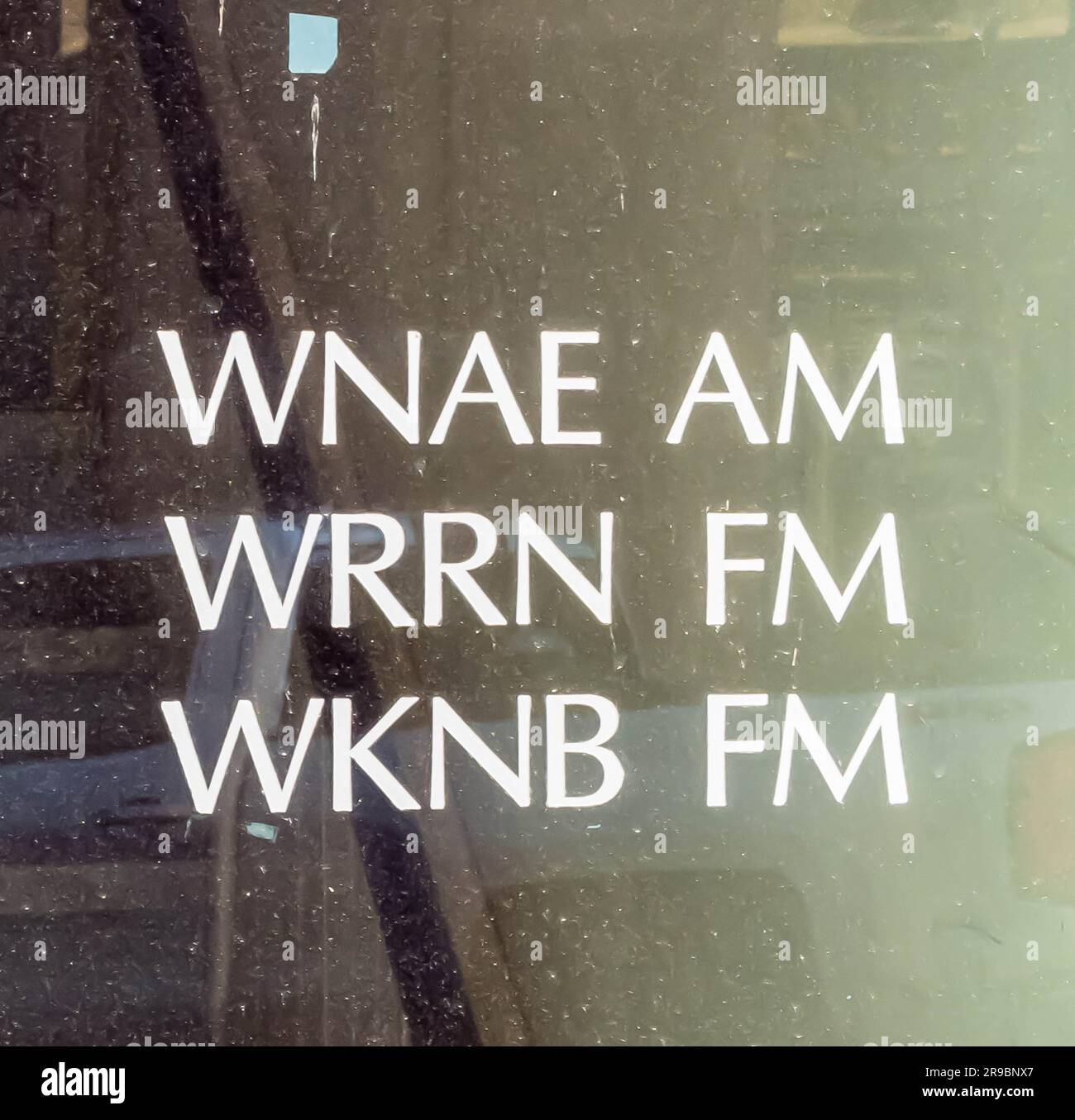 Three radio stations call letters on the dirty glass door to the
