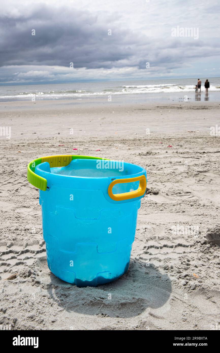 abandoned blue bucket on the sand at the beach, not being played with