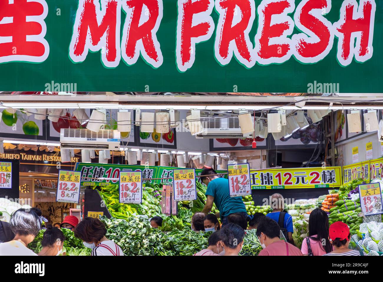 Trader and customers at vegetable shop in Wan Chai market, Hong Kong, SAR, China Stock Photo