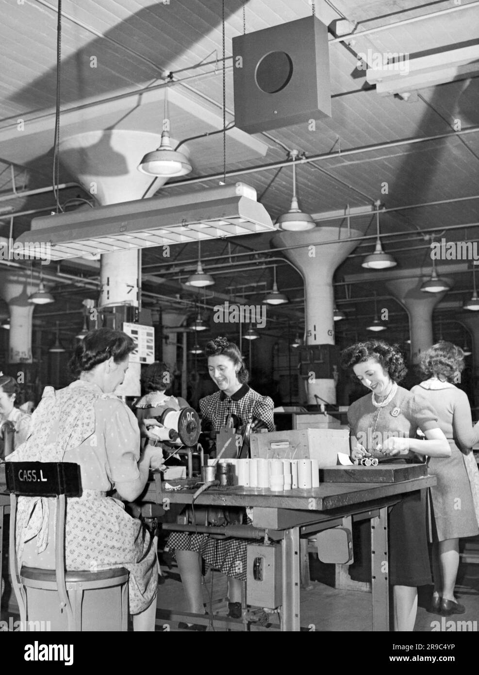 Camden, New Jersey:  c. 1944 Music is broadcast through the overhead speakers to raise employee morale and bring relief to workers on repetitive tasks on this assembly line at a RCA Victor plant. Stock Photo