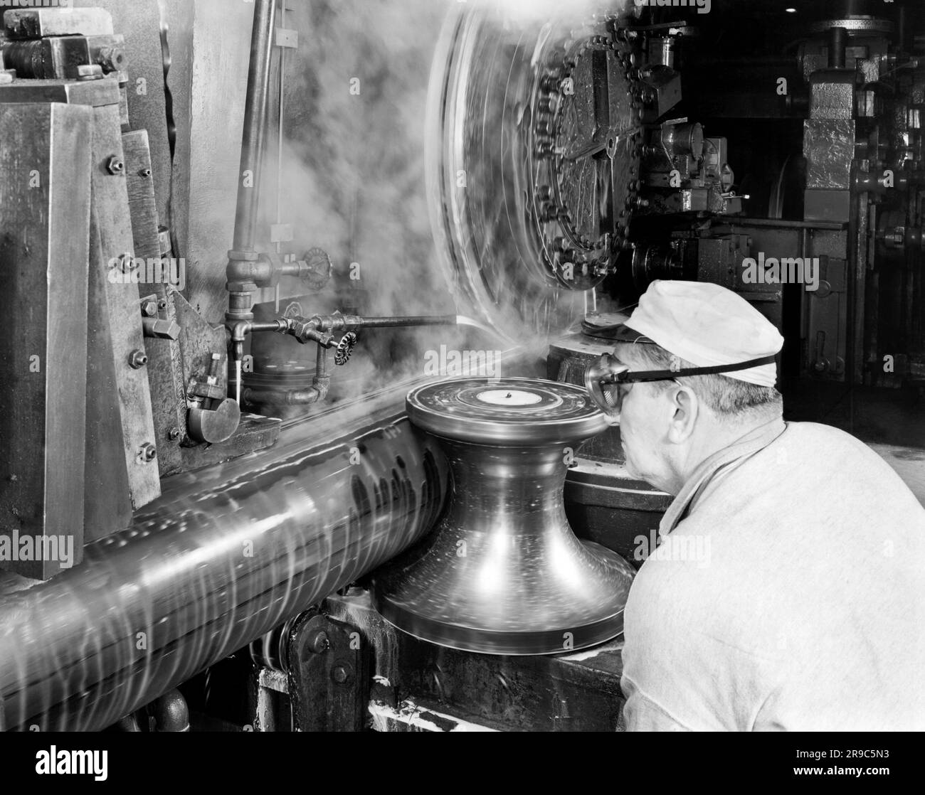 United States c. 1950 A man with safety goggles working at a large industrial grinding machine