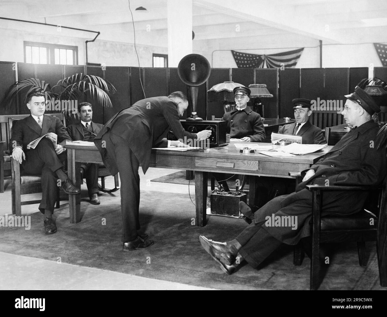New York, New York:  December 17, 1924 Chauffeurs relax and listen to the radio in a 'rest room' while their employers shop. The service was set up by the Franklin Simon Department store, and the cars are parked in a garage to alleviate traffic in front of the store on Fifth Avenue. Stock Photo