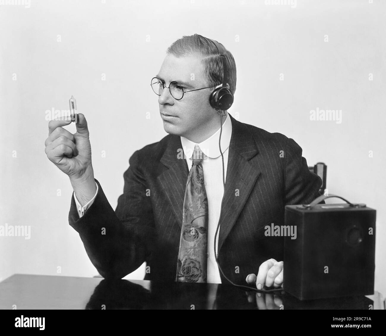 United States:   c. 1926 Inventor Earl C. Hanson holding the the peanut vacuum tube that he used in patenting the first vacuum tube hearing aid called the Vactuphone. Stock Photo