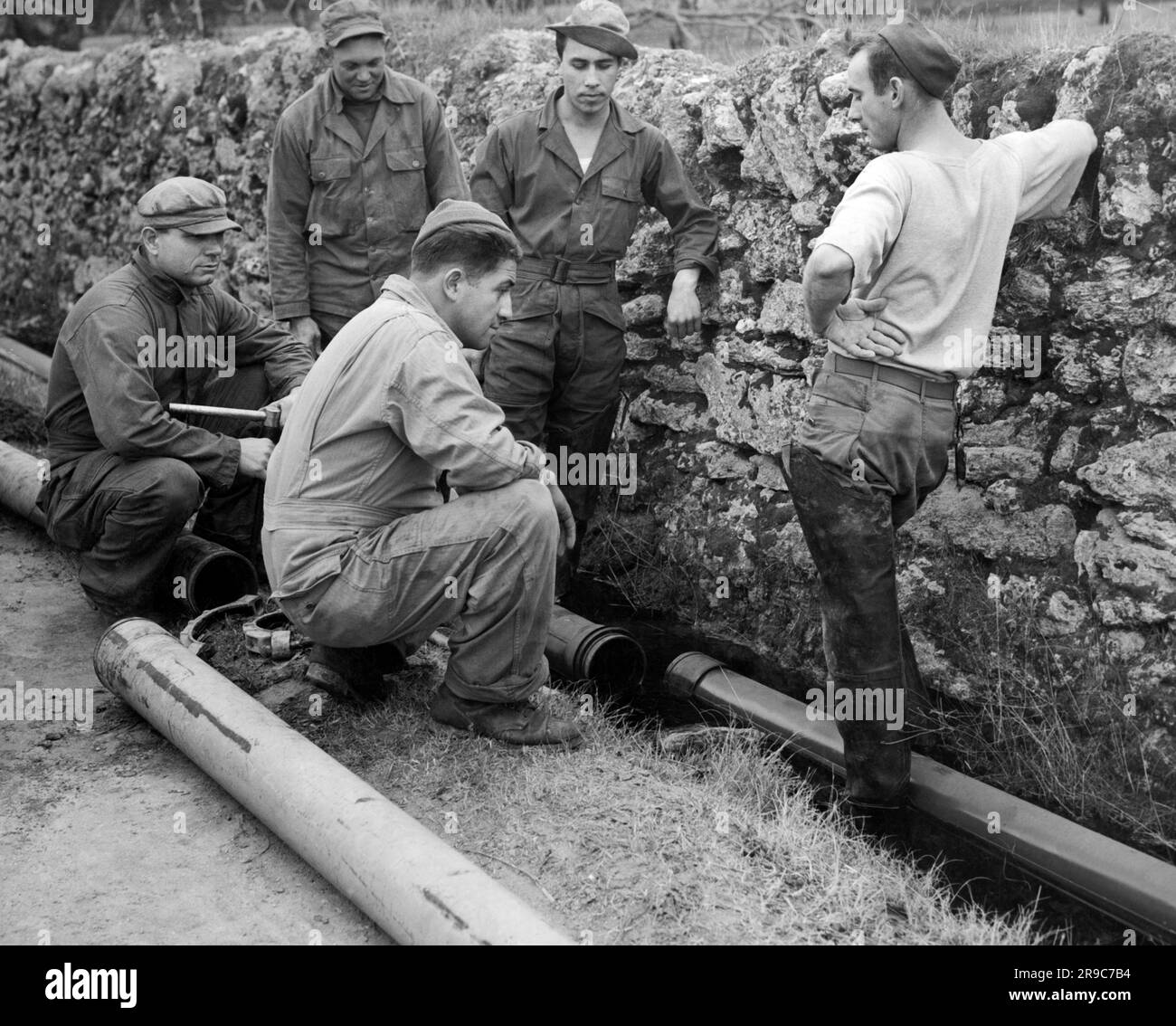 Italy:  c. 1944 Members of the U.S. Army Air Force (AAF) Engineer Command that are responsible for the operation of the pipelines that supply avaiation fuel to all the Allied airfields in Italy. Here they ponder a problem. Stock Photo