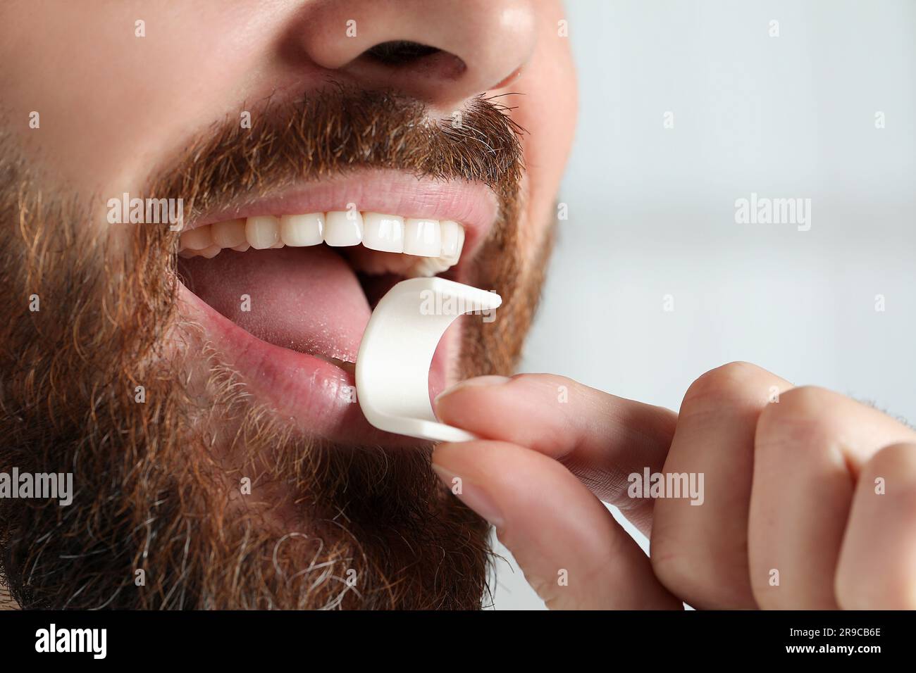 Man putting chewing gum into mouth on blurred background, closeup Stock ...