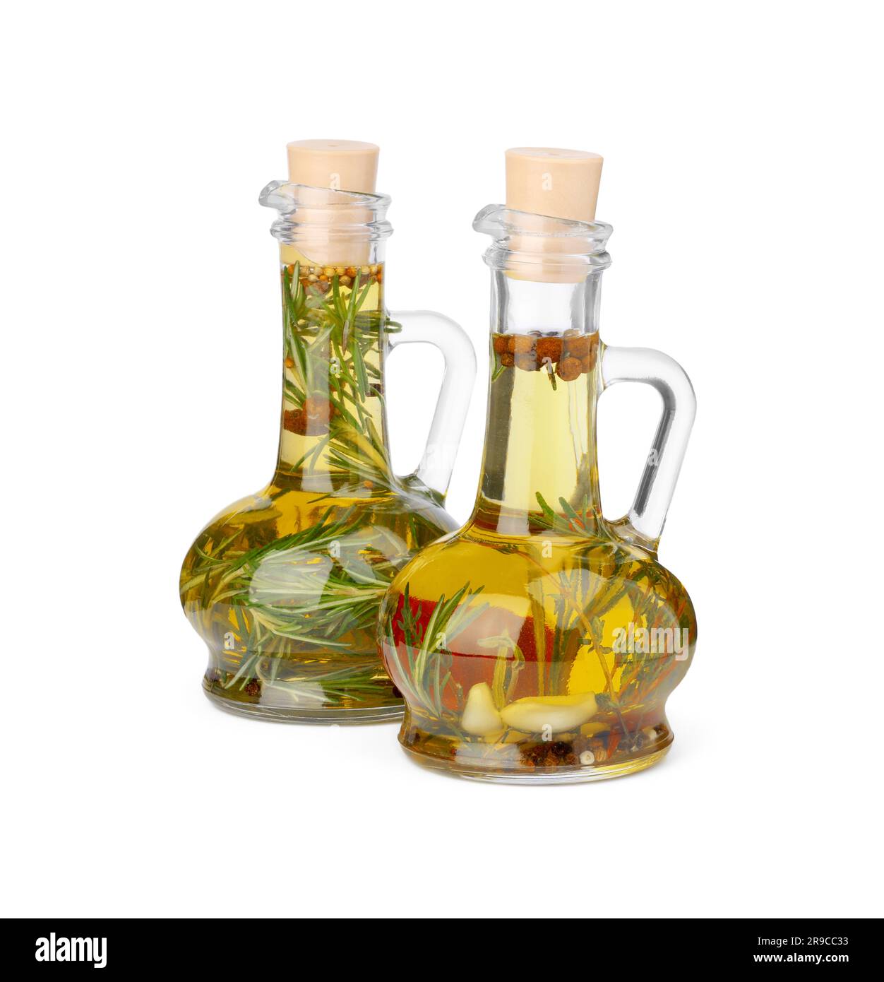 Glass jugs of cooking oils with spices and herbs on white background