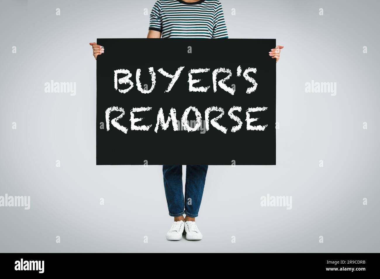 Woman holding poster with text Buyer's Remorse on light grey background, closeup Stock Photo