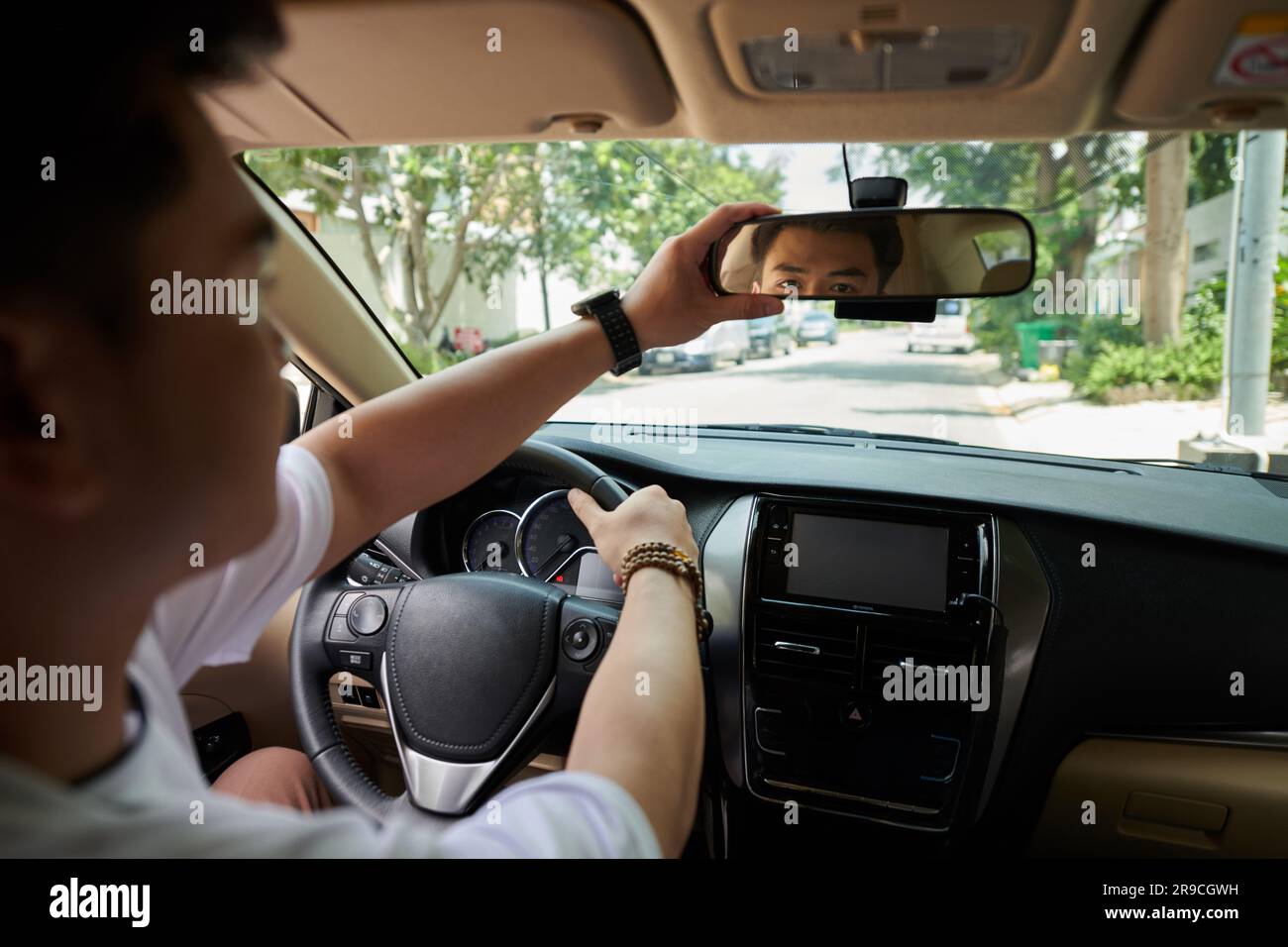 Driver Adjusting Rearview Mirror When Driving To Work In City Street Driver Adjusting Rearview Mirror When Driving To Work In City Street