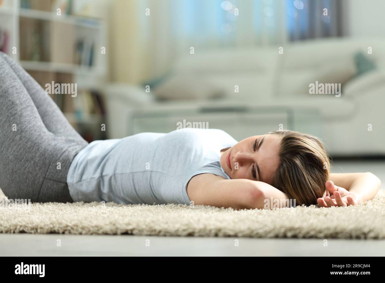 Sad woman lying on a carpet discouraged at home in the night Stock Photo