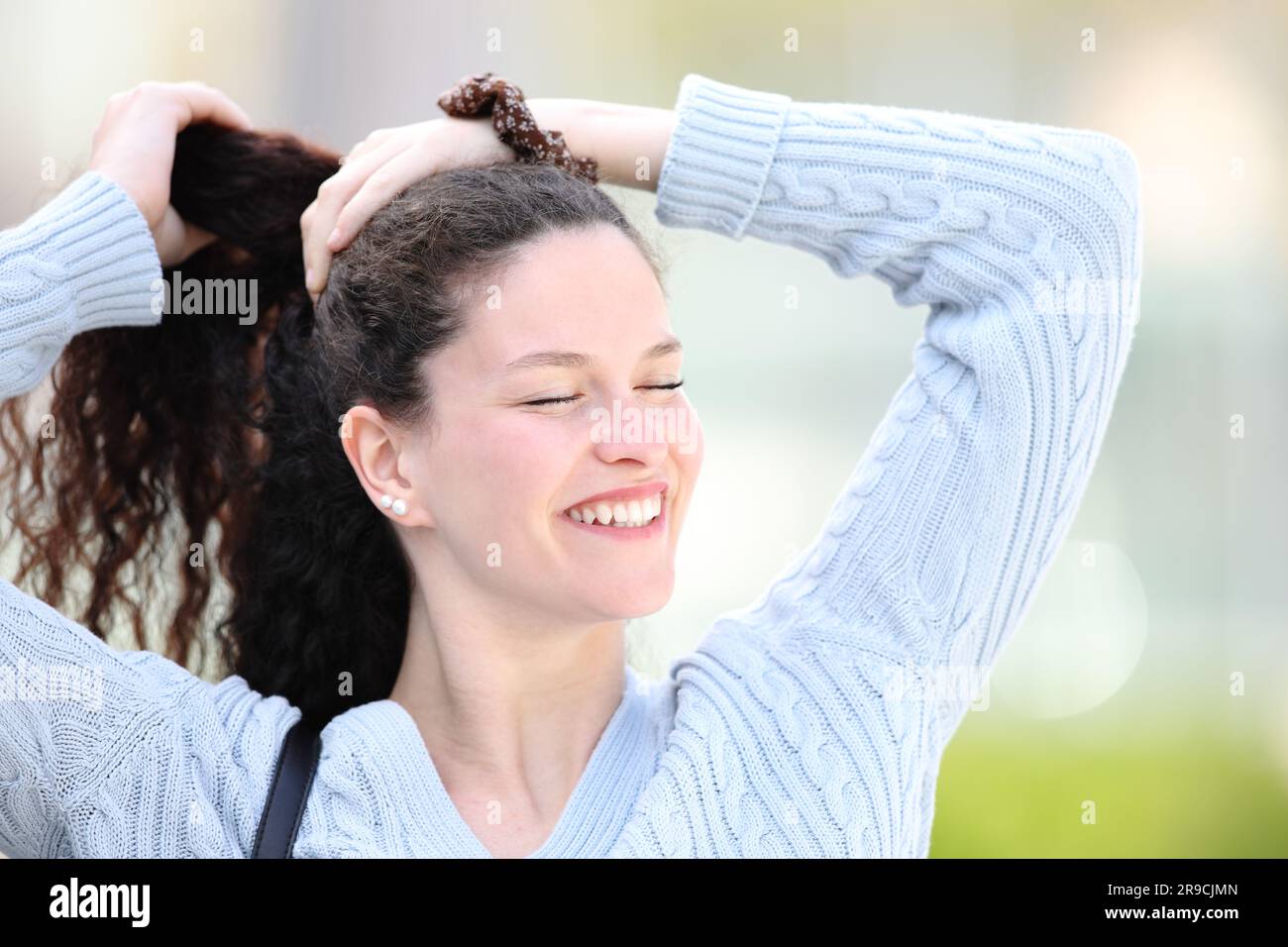 Happy woman walking in the street making ponytail Stock Photo