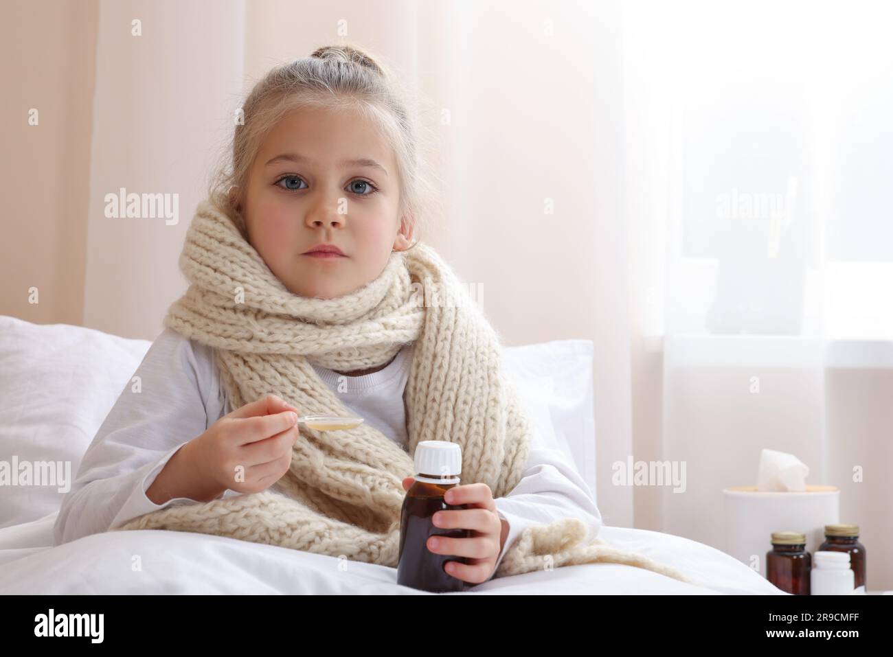 Sick girl taking cough syrup on bed at home, space for text. Cold