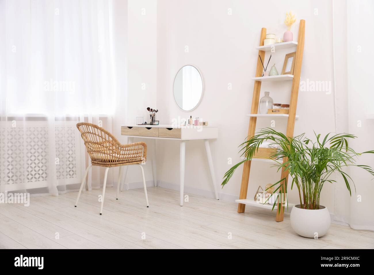 Stylish room with white dressing table, shelving unit and houseplant