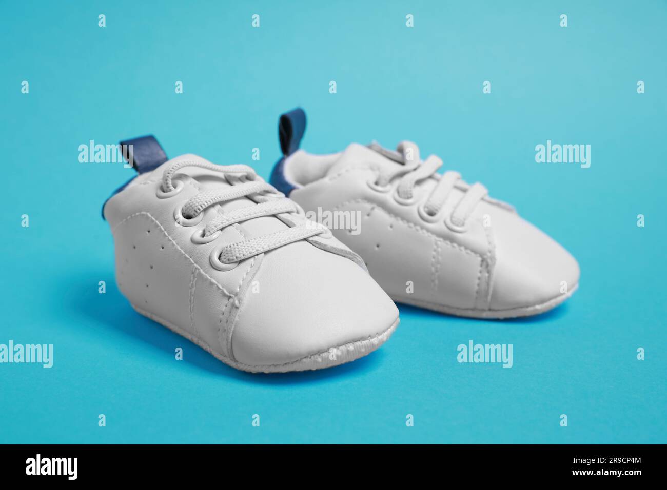 Pair of cute baby shoes on light blue background Stock Photo - Alamy