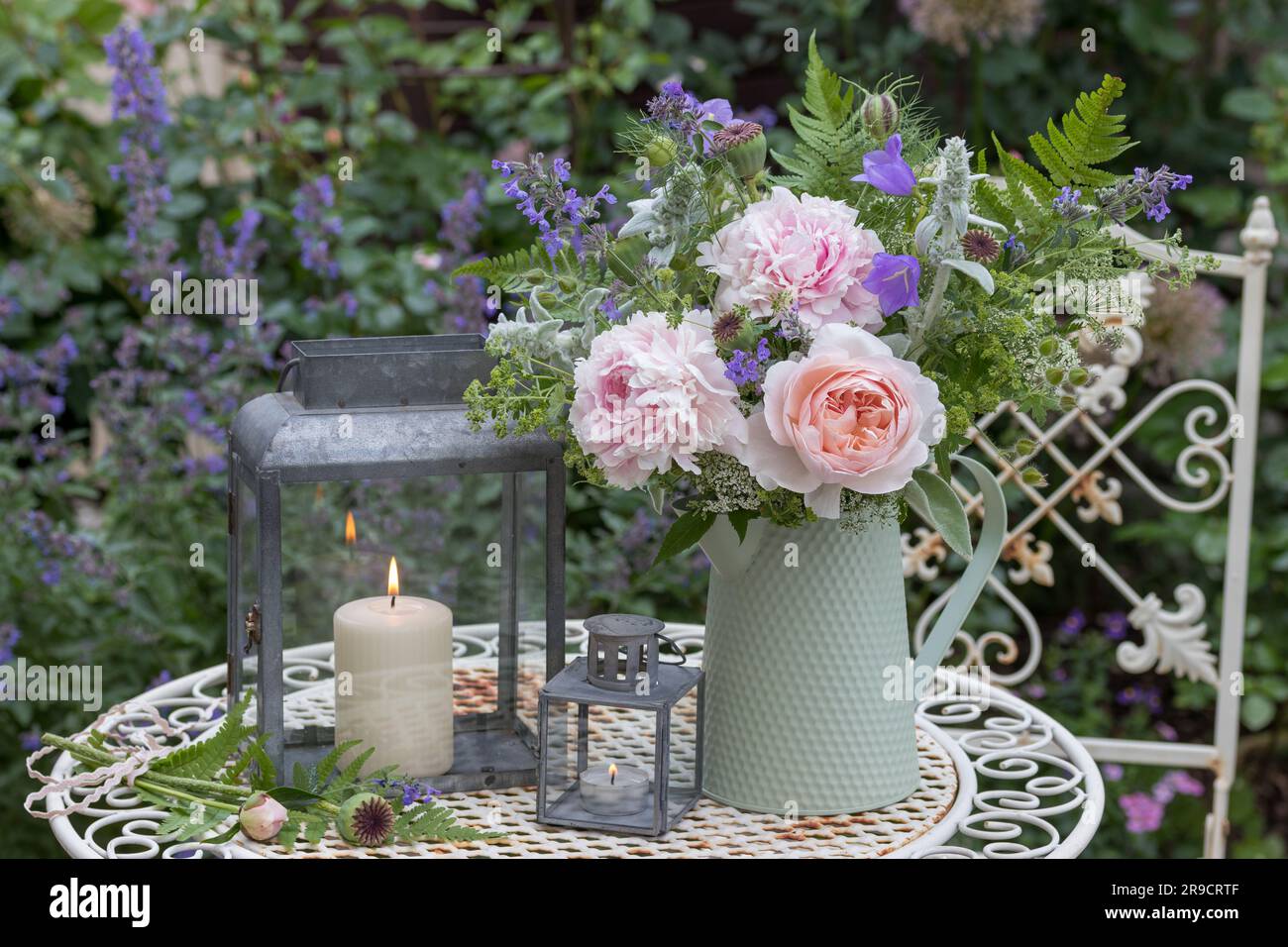garden arrangement with bouquet of rose, peonies and summer flowers and zinc lanterns Stock Photo