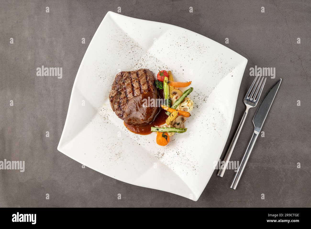 Grilled beef tenderloin with Demi glace sauce with grilled vegetables on a white porcelain plate Stock Photo