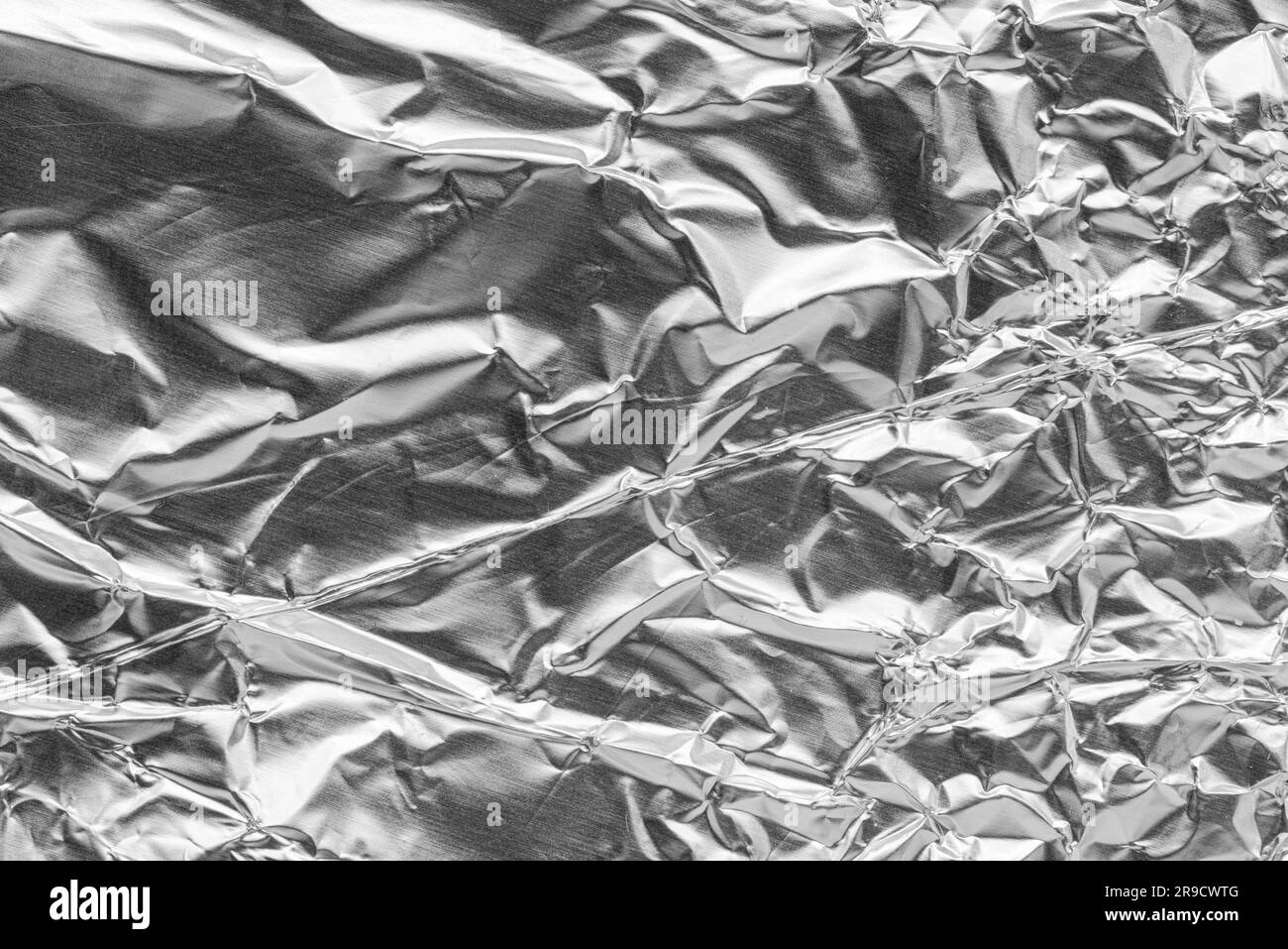 Crumpled bright shiny metallic silver aluminium foil background, flat lay view backdrop with copy space for text Stock Photo