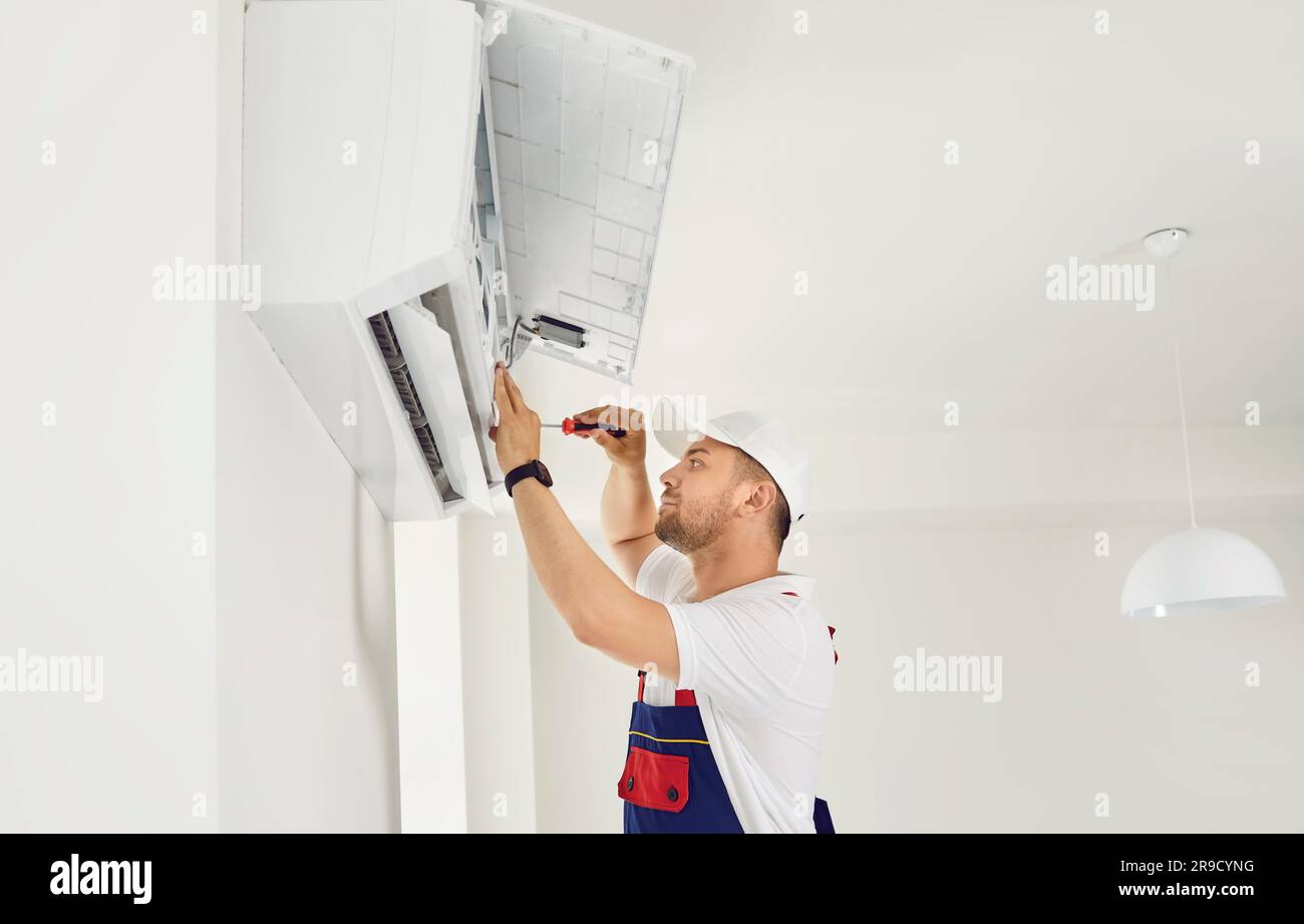 Repairman installing or repairing a modern air conditioner on the wall