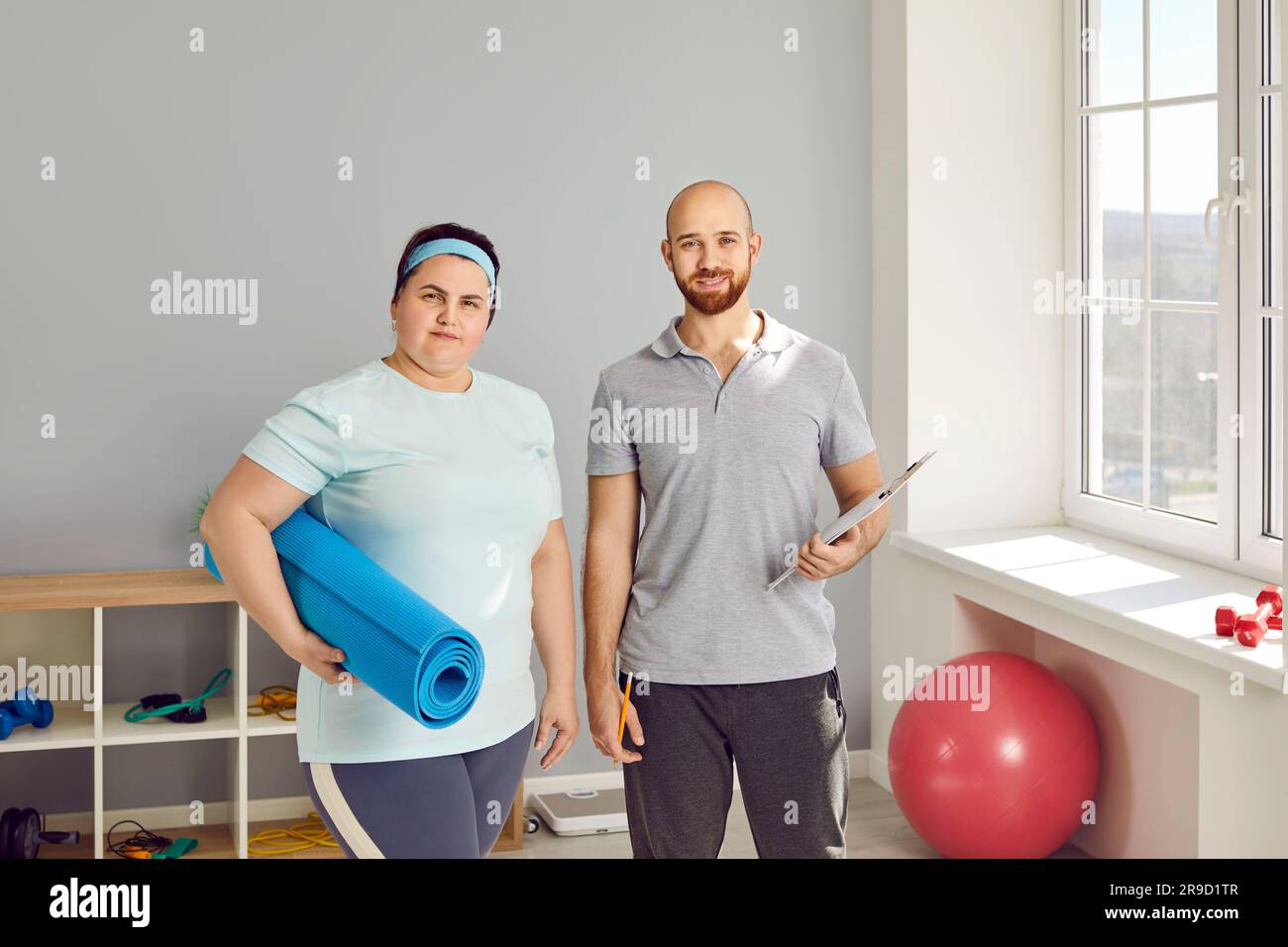 Fat young woman standing with a male young nurse and looking at the camera. Stock Photo
