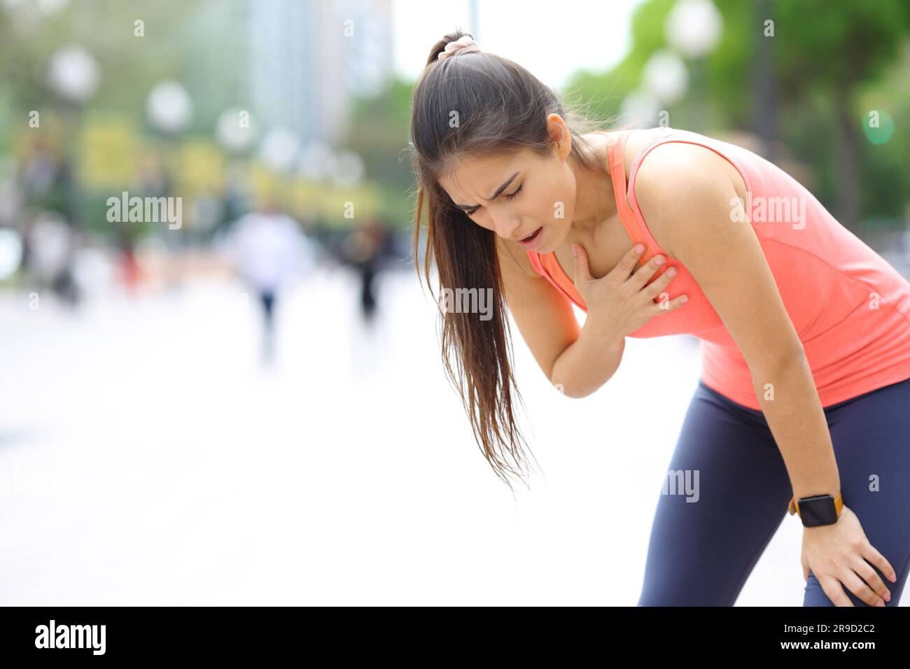Exhausted runner touching chest breathing in the street Stock Photo