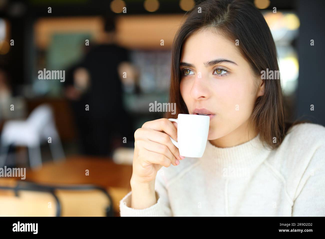 Serious woman drinking coffee alone in a bar looking away Stock Photo