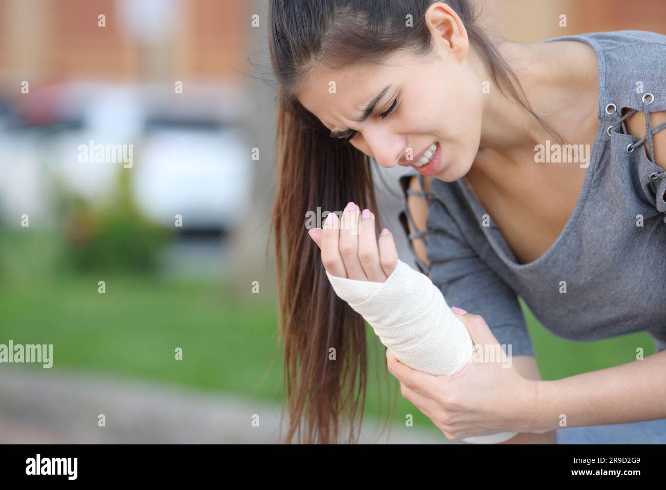 Woman suffering with bandaged sprained wrist in the street Stock Photo