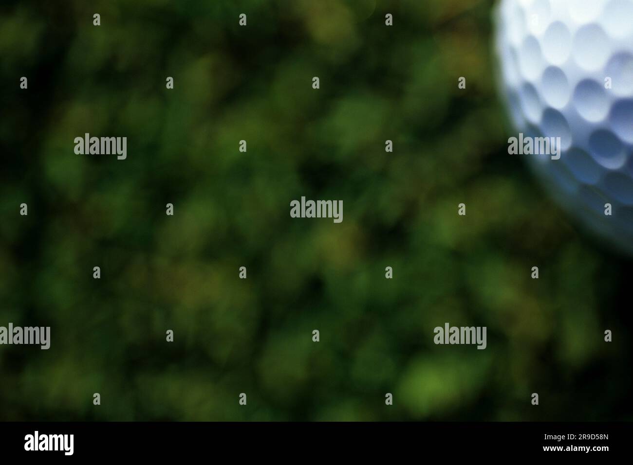 Closeup of portion of golf ball in upper corner of frame with grass