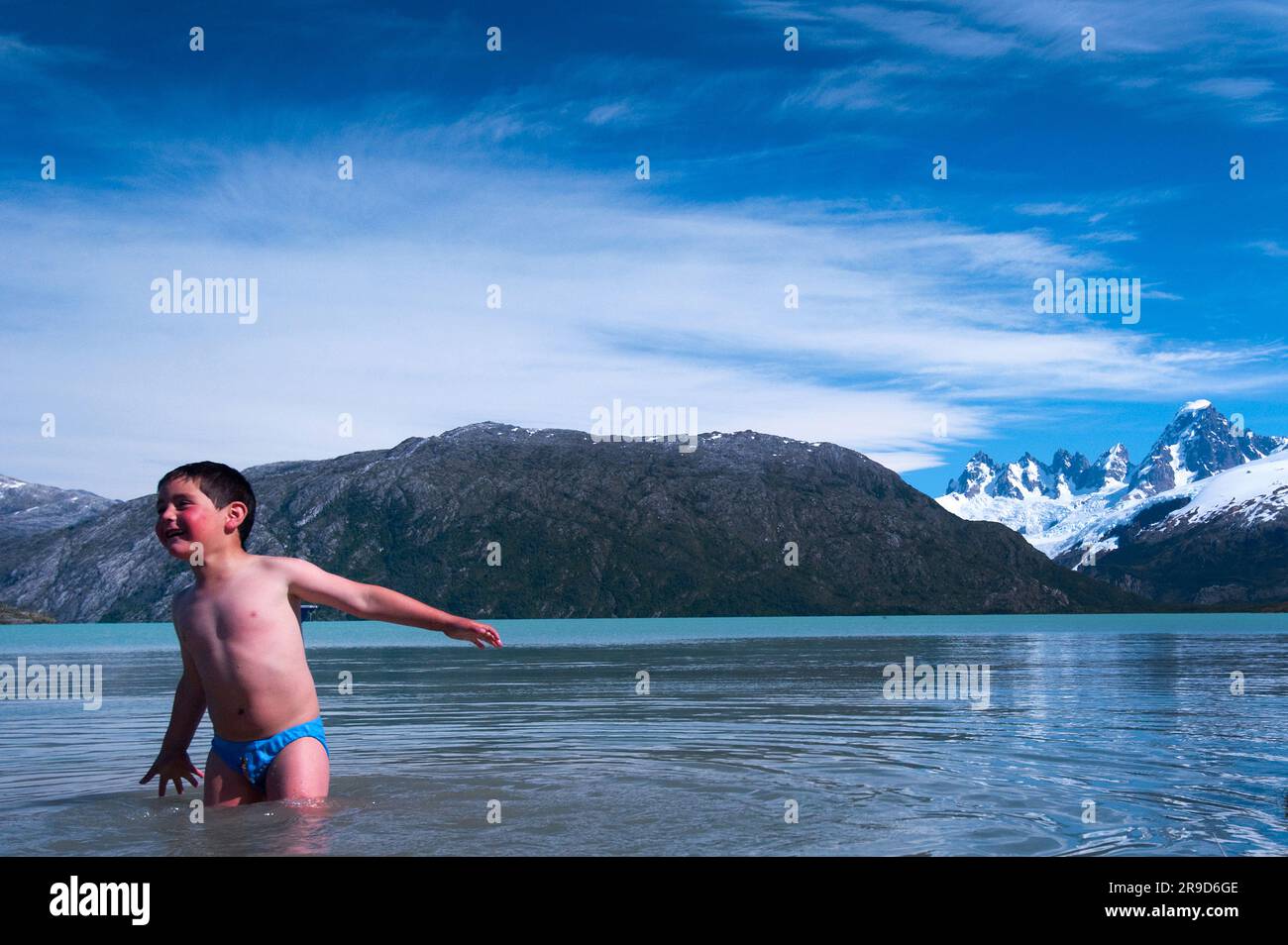 A boy plays in the icy glacial waters of Lake O'Higgins, Chile. Stock Photo