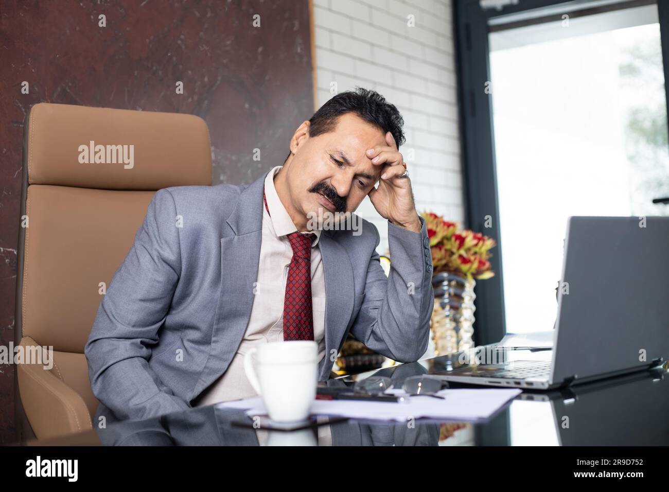 Tired And Stressed Mature Indian Businessman After Working Long Hours
