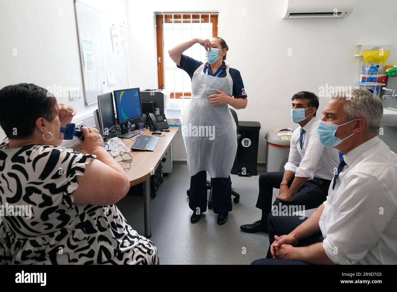 Prime Minister Rishi Sunak with Health Secretary Steve Barclay speaking to patient Susan (no surname given) as she takes a Spirometry Test during a visit to Rivergreen Medical Centre in Nottingham. Picture date: Monday June 26, 2023. Stock Photo