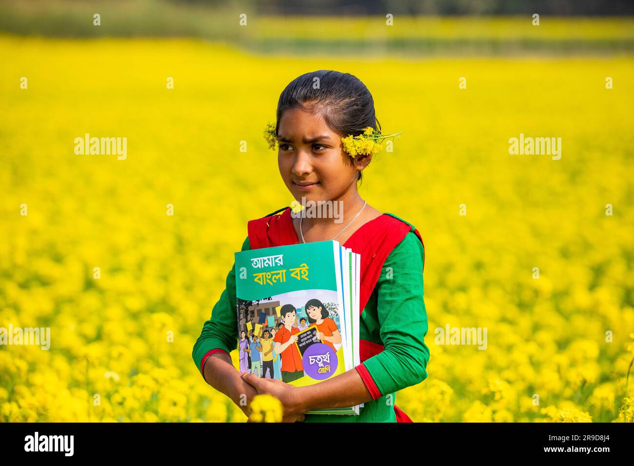 School girl in a Bangladeshi village, holding a board, with friend in the background Stock Photo
