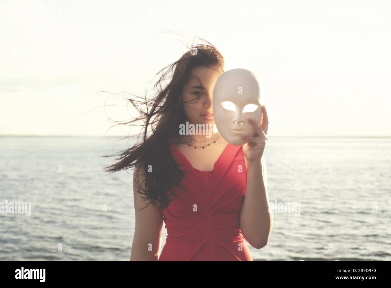 woman hiding half face behind a mask, abstract concept Stock Photo