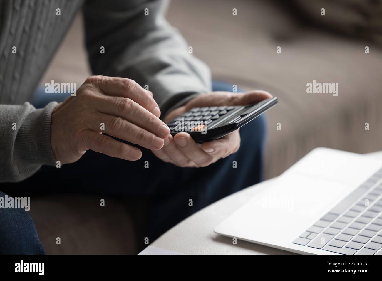 Senior man using calculator calculates expenses and incomes Stock Photo