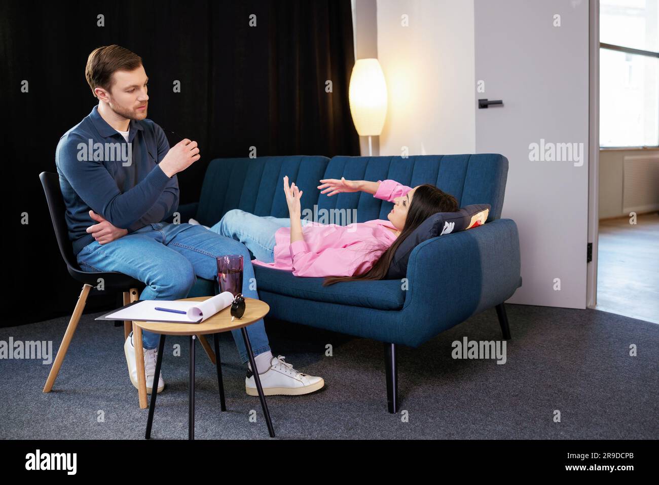 Attractive woman reclining comfortably on a couch talking to his psychiatrist explaining something. Stock Photo