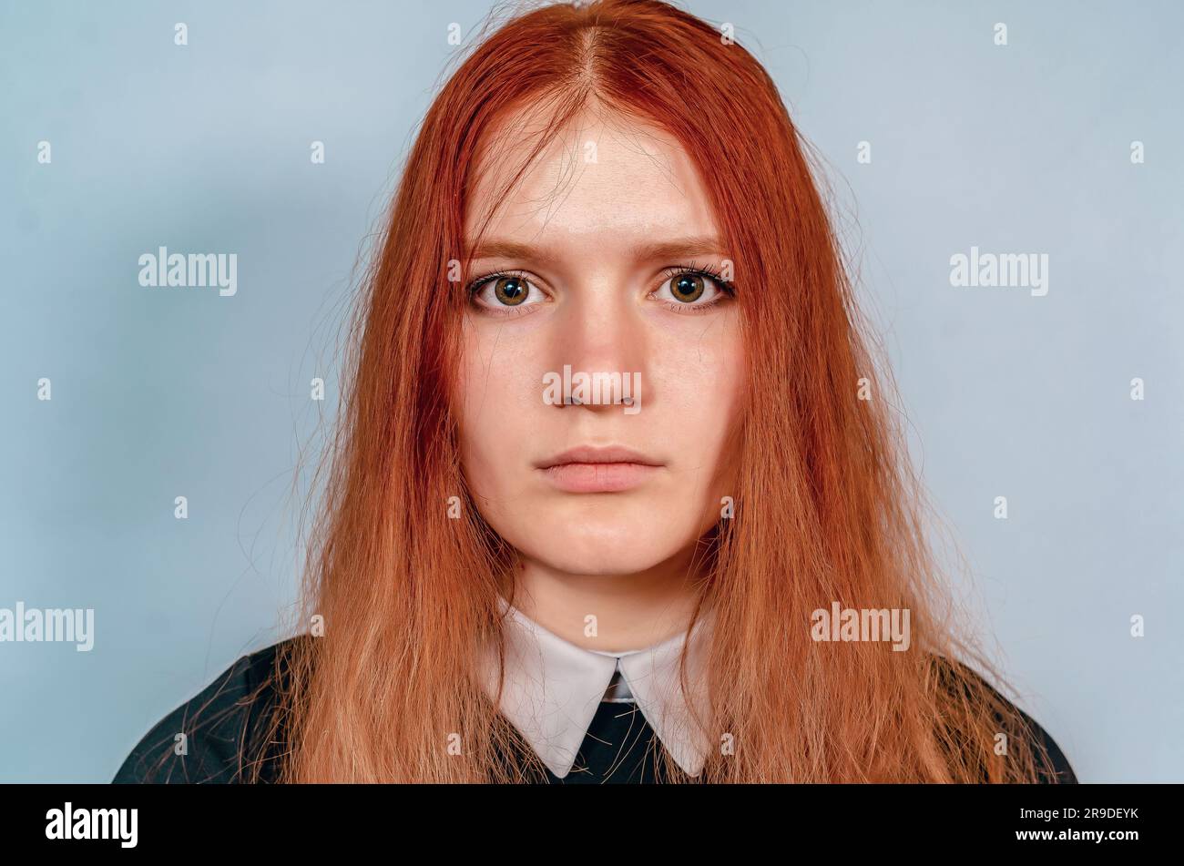 Portrait of serious redhaired girl in black dress with white collar