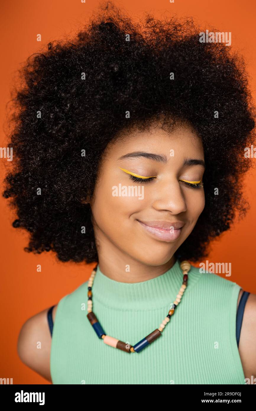 Portrait of joyful and teen african american girl with bold makeup