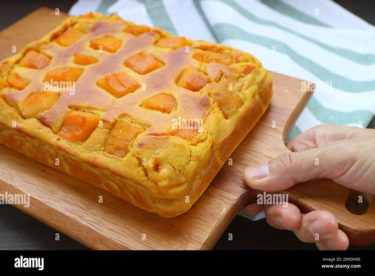 Hand Holding a Breadboard of Freshly Baked Pumpkin Cake Stock Photo